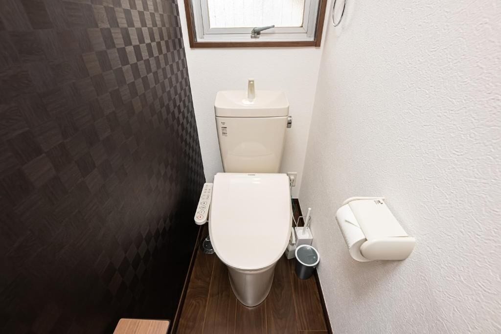 Baño compacto con inodoro, bidé y secador de manos.