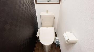 Baño compacto con inodoro, bidé y secador de manos.