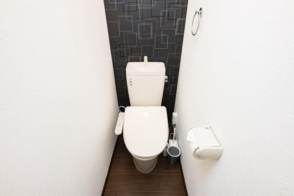 Een moderne badkamer met een toilet, een douchetoilet en een handdroger.