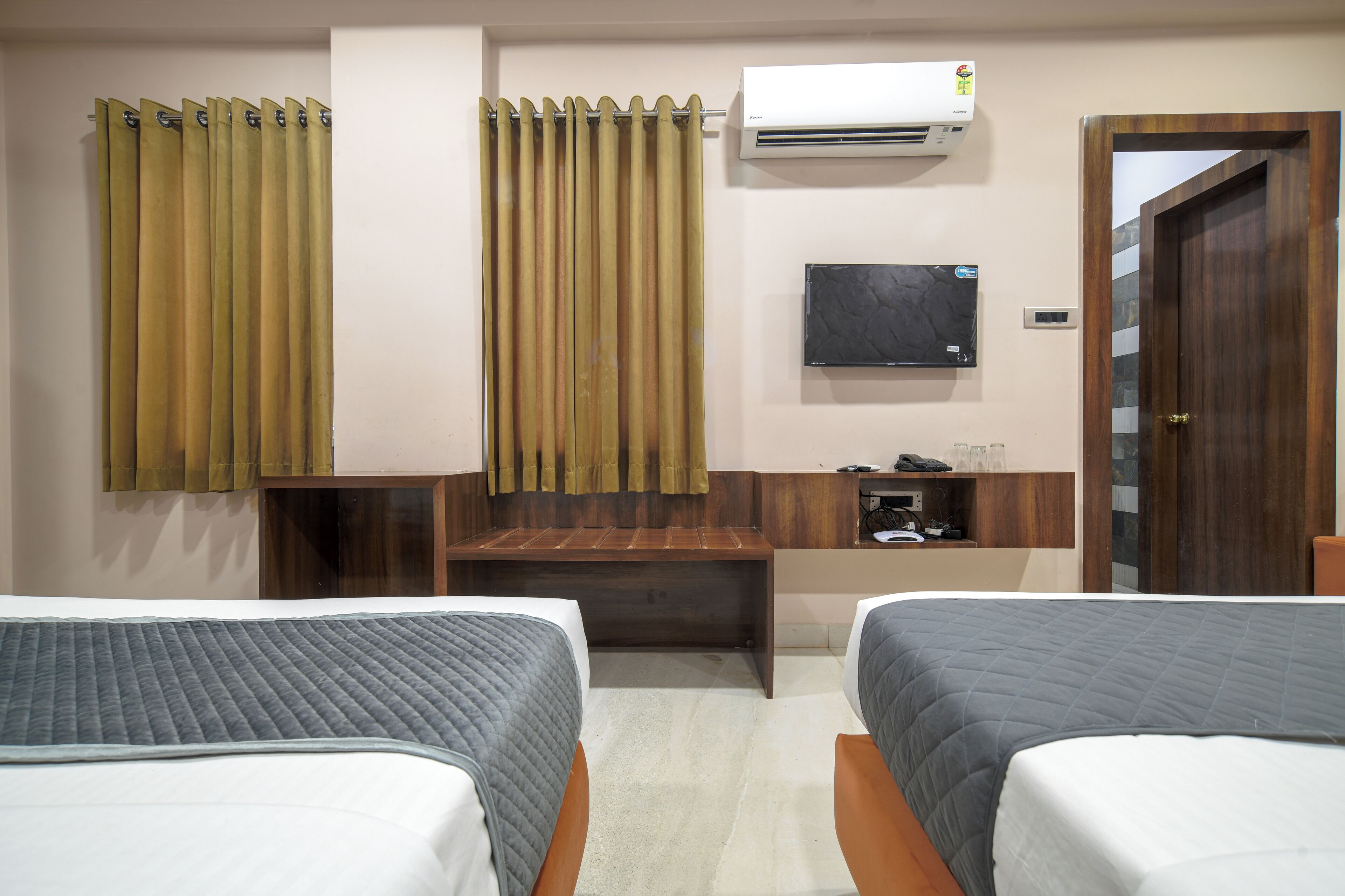 Habitación de hotel con dos camas, un escritorio, un televisor y un aire acondicionado.
