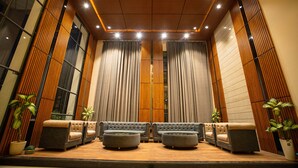 A spacious lobby with a modern design, featuring a seating area with sofas and ottomans, wooden paneling, and large windows. - Hotel Miracle  (Ujjain)