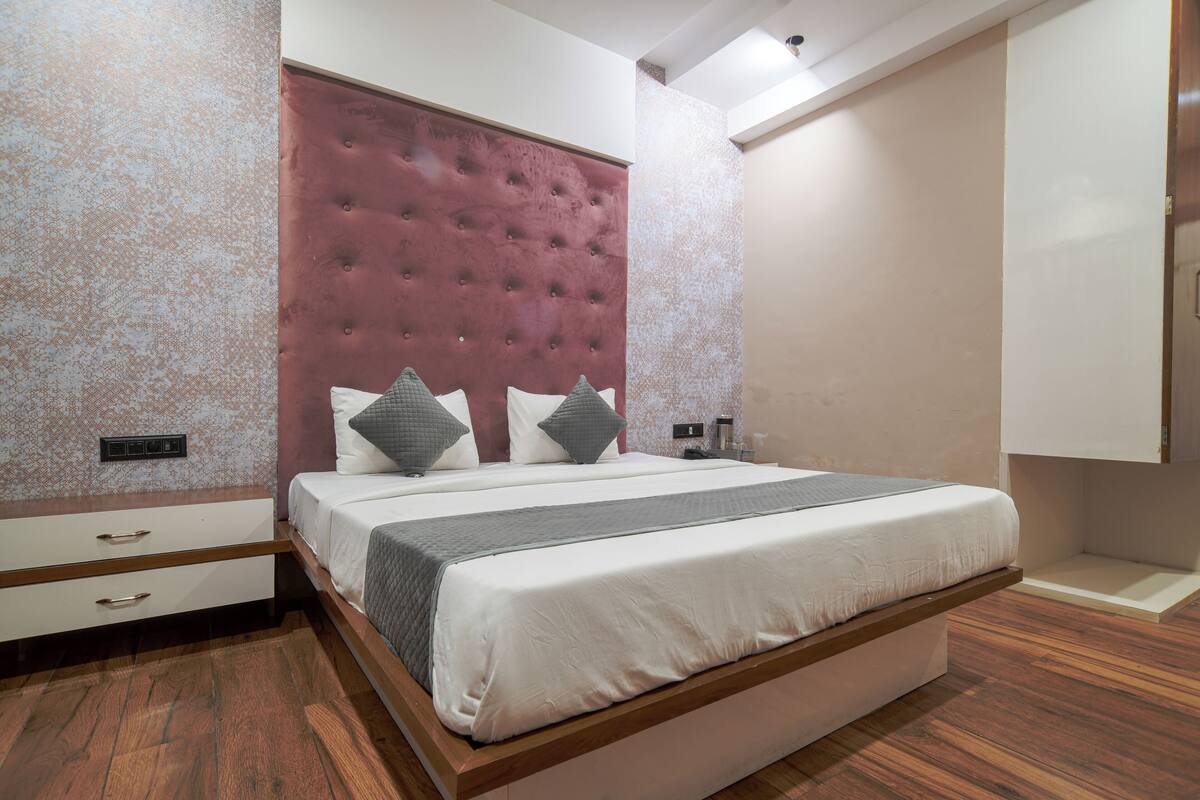 A modern bedroom with a large bed, a tufted headboard, and a wooden floor.