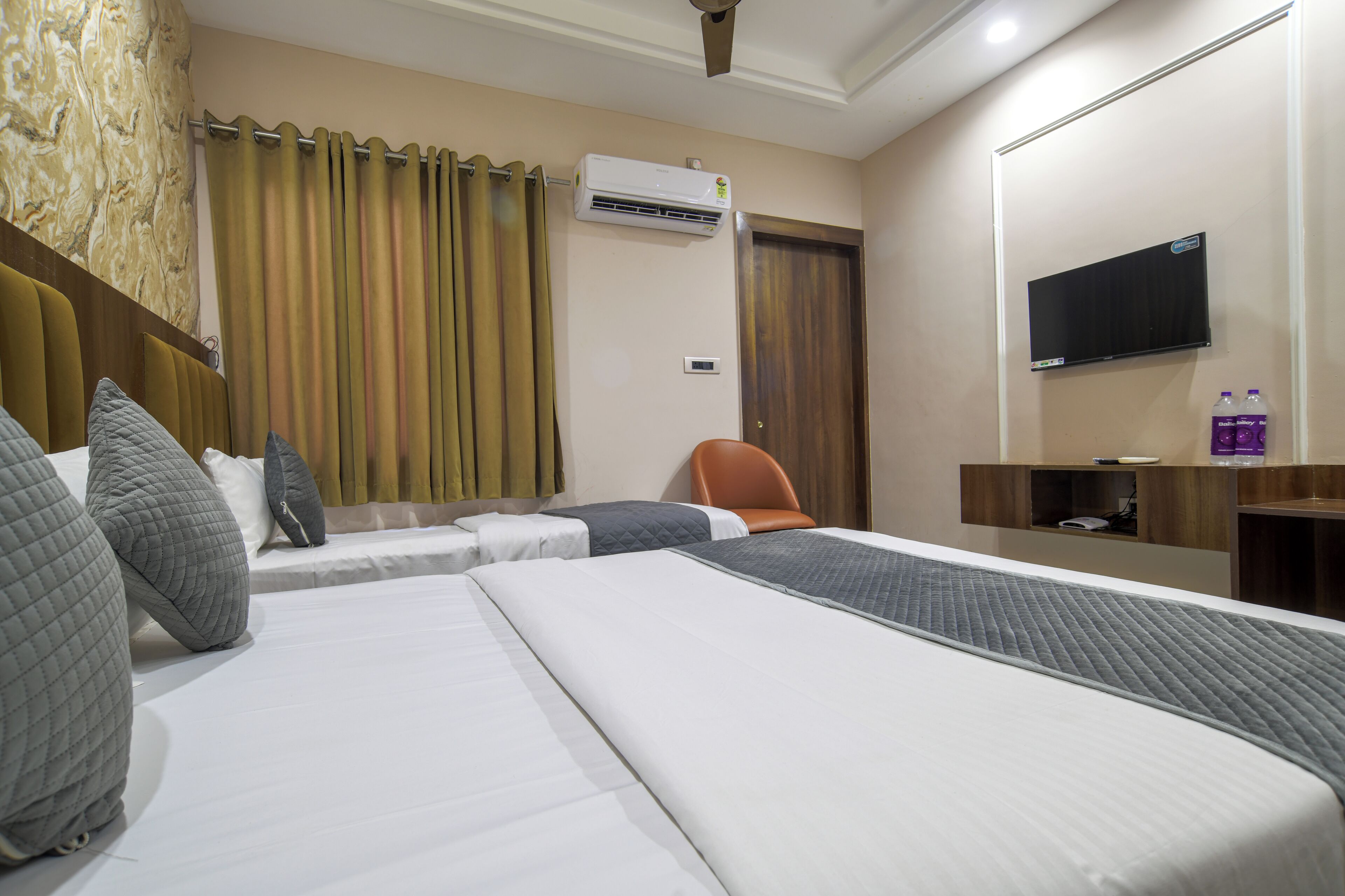 Une chambre d’hôtel avec un grand lit, une chaise, un téléviseur et un appareil de climatisation.