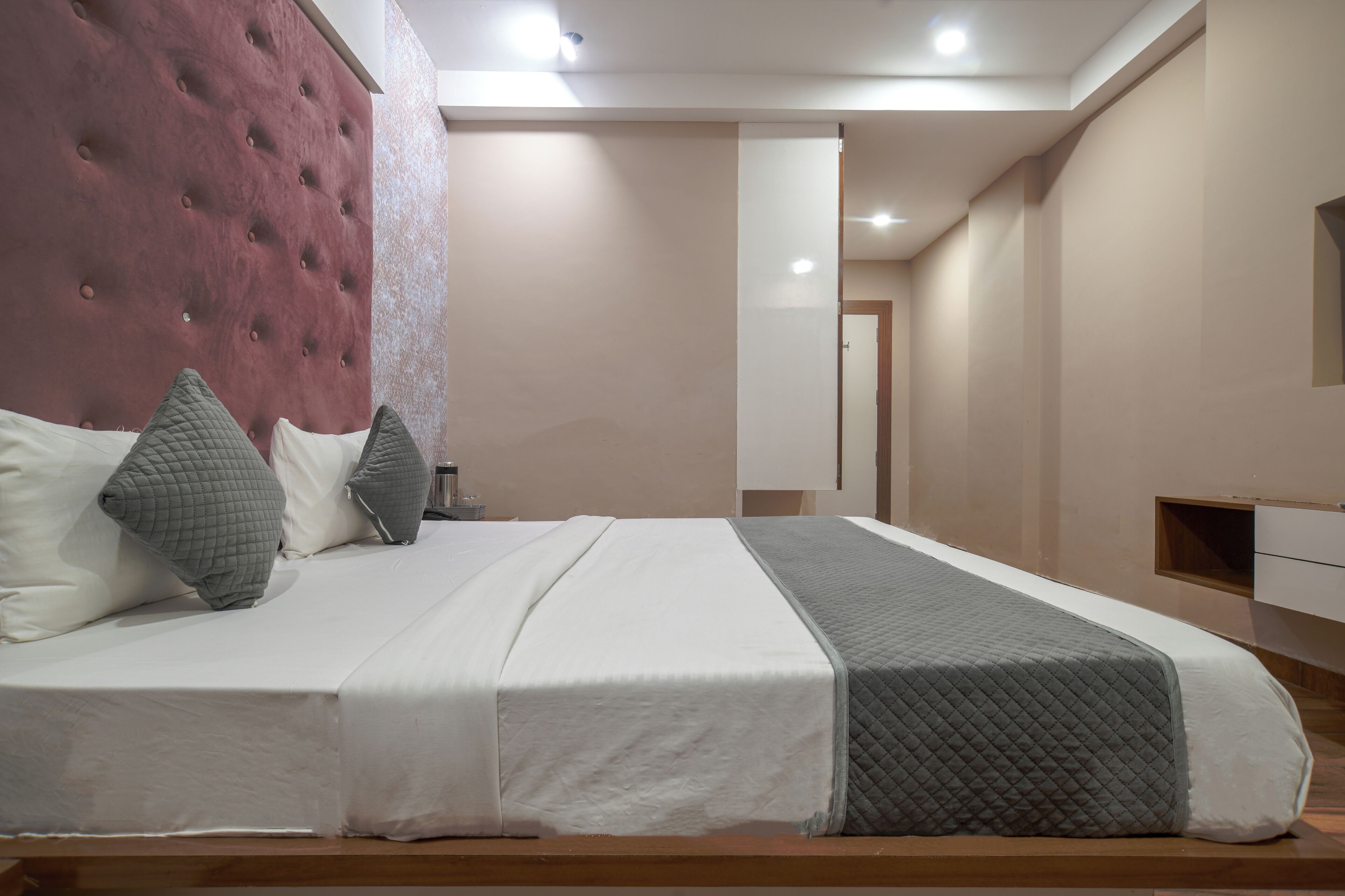 A modern bedroom with a large bed, a tufted headboard, and a neutral color scheme.