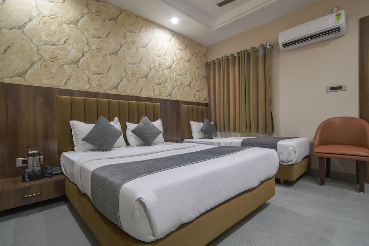 A hotel room with two beds, a wooden headboard, a coffee machine, and an air conditioning unit on the wall.