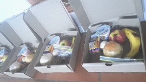 Cuatro cajas de alimentos con diferentes productos como manzanas, plátanos y productos envasados.