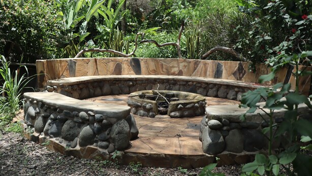 Un hogar de piedra rodeado por una zona de asientos curva con un muro de piedra.