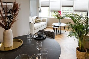 Enjoy meals and social gatherings around the round dining table, surrounded by a comfortable sofa and lush greenery.