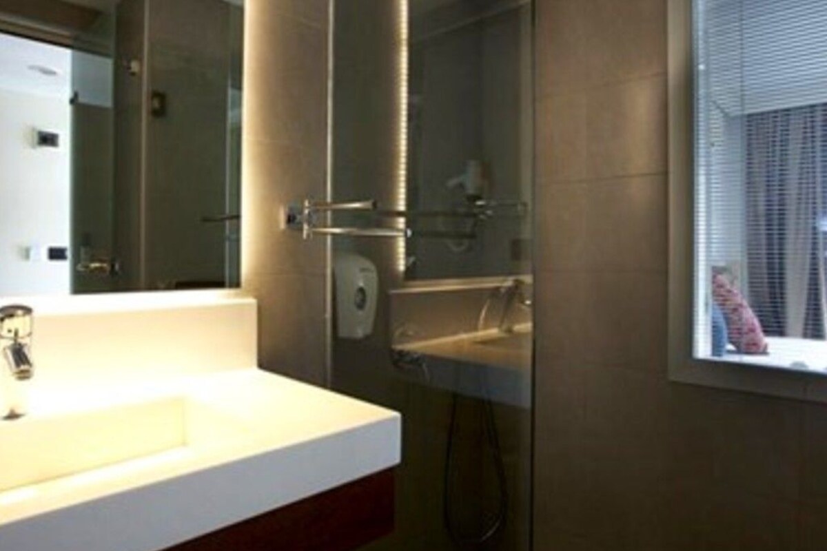 A modern bathroom with a glass shower enclosure, a white sink, and a mirror.
