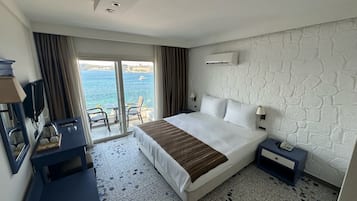 Habitación de hotel con cama, escritorio, silla, televisión y vista al mar.