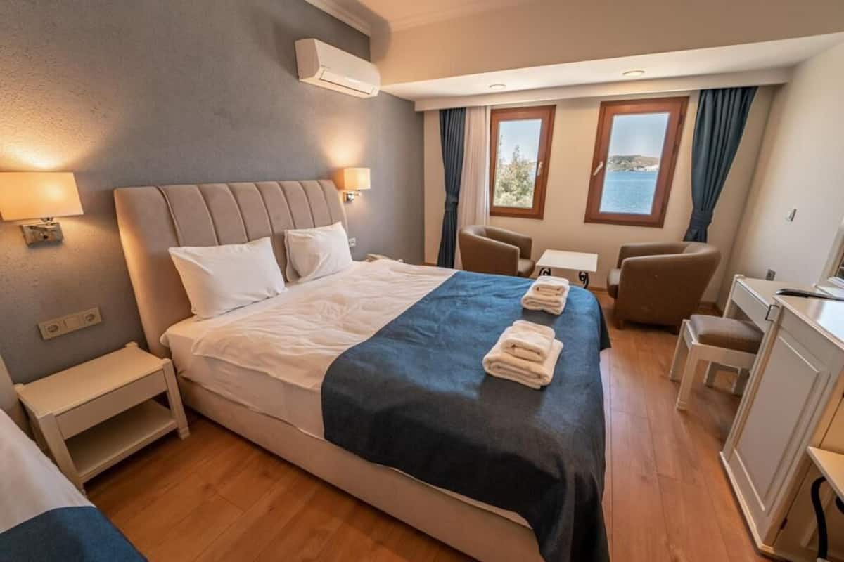 A hotel room with a large bed, bedside tables, a desk, and a chair.