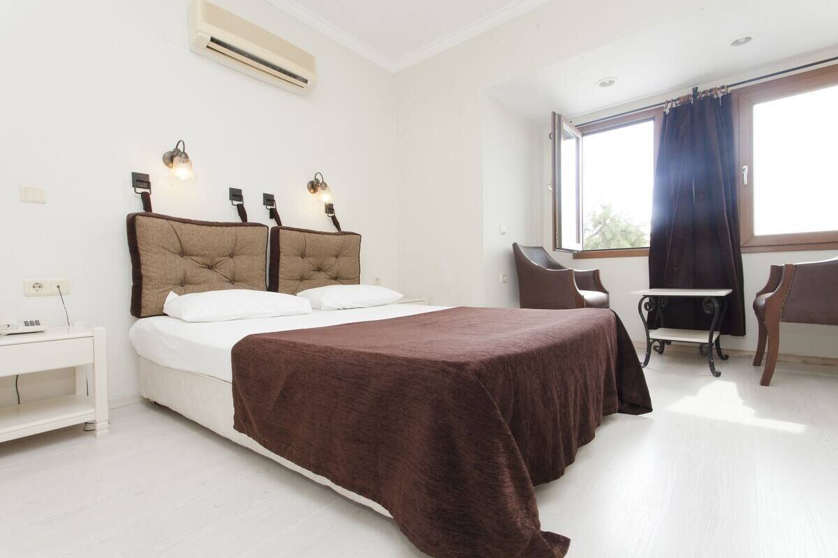 A modern bedroom with a bed, bedside tables, a desk, and a window with curtains.