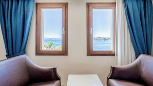 A room with two windows, a table, and two leather chairs. - Bodrum Gulet Otel (Bodrum)