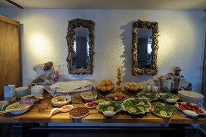 A buffet table with various food items and two wall-mounted mirrors. - Bodrum Gulet Otel (Bodrum)
