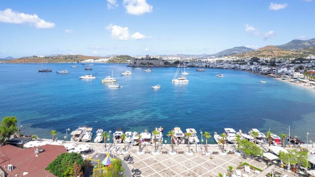 A marina with boats docked, a bridge, and a coastal town in the background. - Bodrum Gulet Otel (Bodrum)