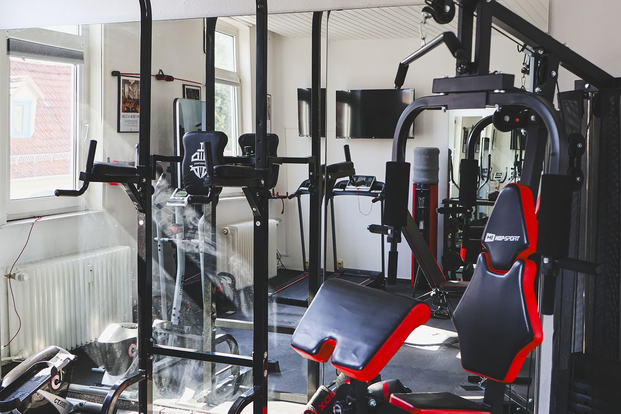 Una palestra con attrezzi per esercizi, una panca e una finestra.