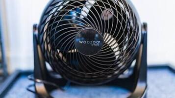 En sort, bærbar ventilator med et cirkulært gitter og mærket "WooZoo" synligt på forsiden.