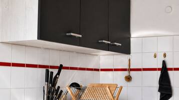 Una cocina con un armario negro, un lavamanos de acero inoxidable y una tabla de cortar de madera.