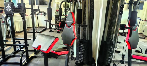 Une salle de sport équipée de divers appareils d’exercice, notamment des appareils de musculation et des tapis de course.
