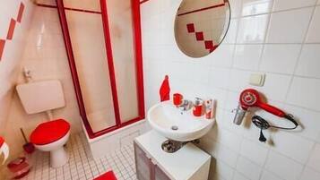 Een badkamer met toilet, wastafel en douche.