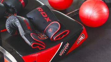 A gym with exercise equipment, including a red and black punching bag, a red exercise ball, and a black weight bench.