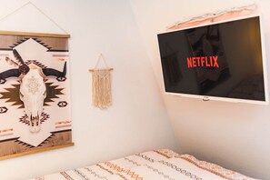 A room with a bed, a wall-mounted TV displaying 'NETFLIX', and decorative wall art including a skull and macramé. - 🧭Bohemian Paradise🧭 incl. Extras (Göttingen)