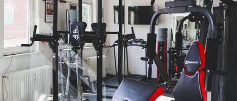 A gym with exercise equipment, a bench, and a window.