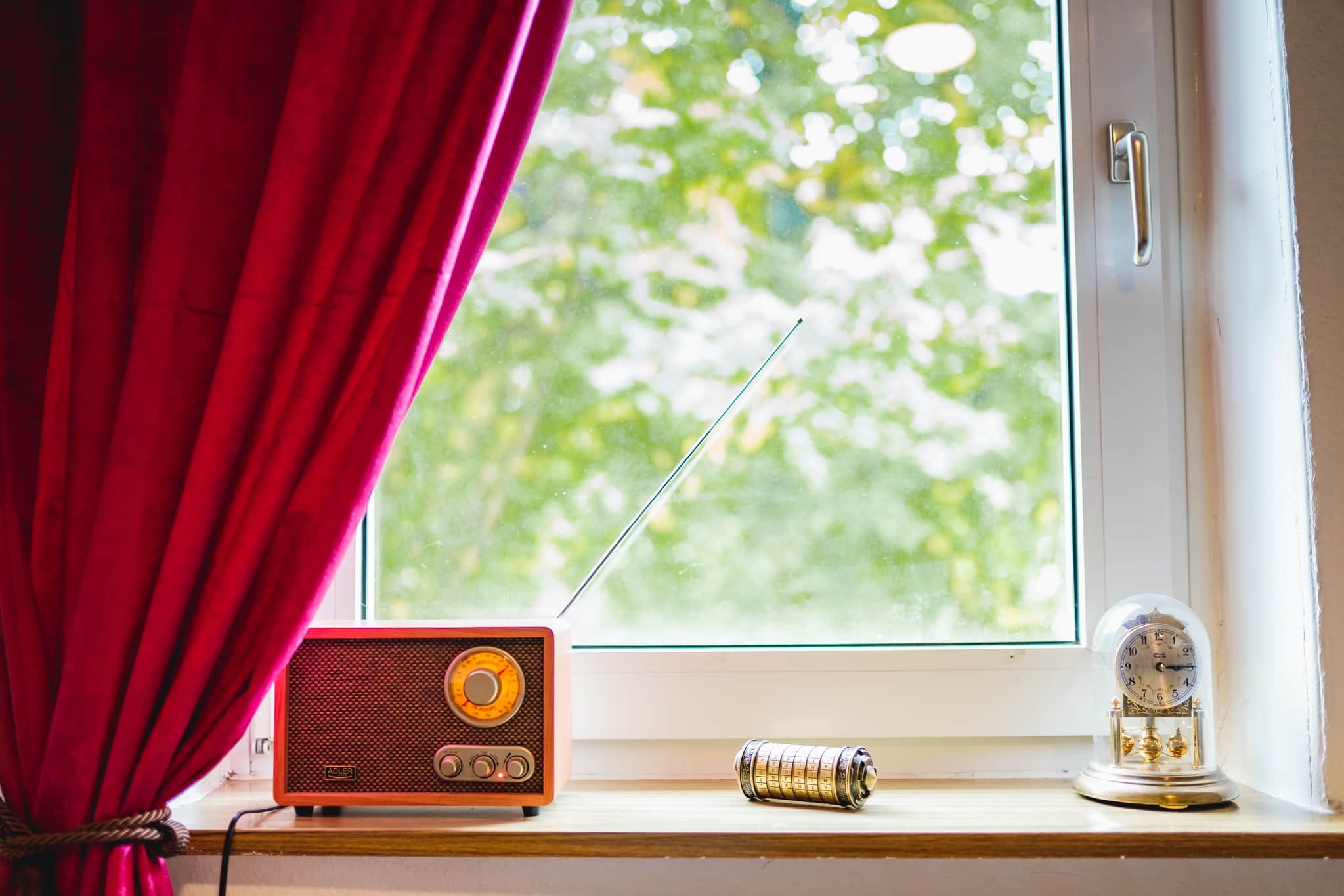 Een oude radio op een vensterbank, met uitzicht op groen buiten.