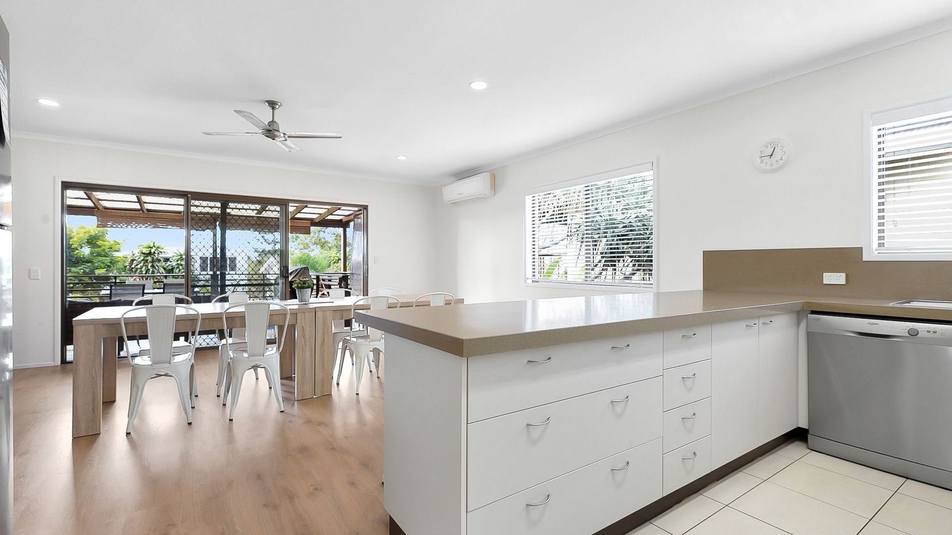 A modern kitchen with a central island, white cabinetry, and a built-in dishwasher.
