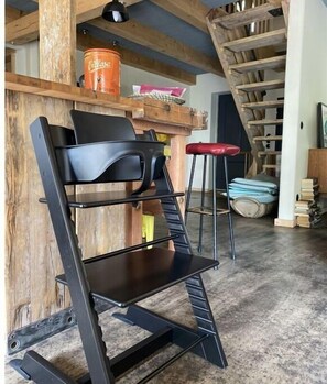 A chair sits against a wall, accompanied by a wooden ladder and a metal shelf.