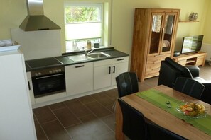 Une cuisine équipée d’une cuisinière, d’un four, d’un évier, ainsi que d’un coin repas avec une table et des chaises.