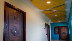 A hallway with wooden doors, a tiled floor, and a yellow ceiling. - Bala Residency  (Puducherry)