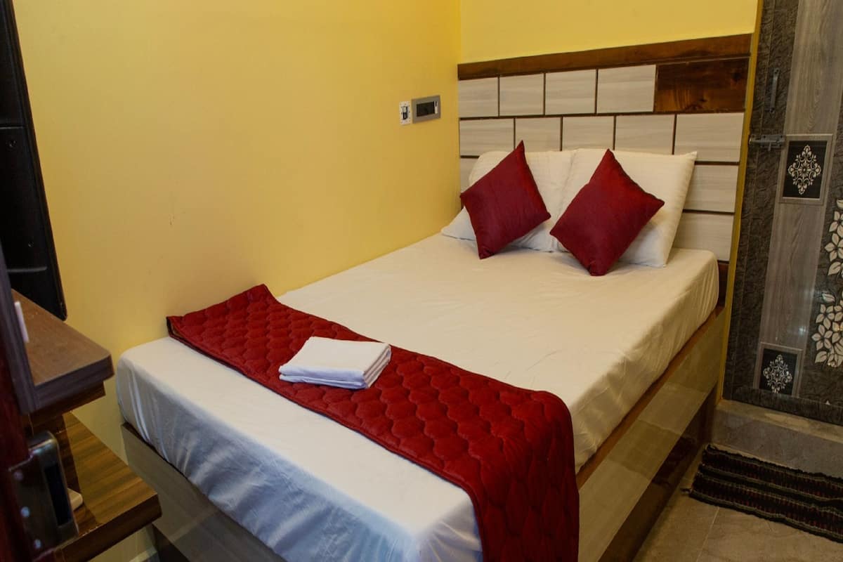 Una cama bien hecha con una colcha y almohadas rojas, un cabecero de madera y un suelo de mármol.
