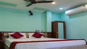 A hotel room with a bed, a ceiling fan, an air conditioning unit, and a wardrobe. - Bala Residency  (Puducherry)