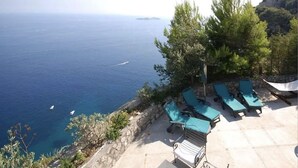 Una terraza frente al mar con sillones de descanso y vistas al océano.