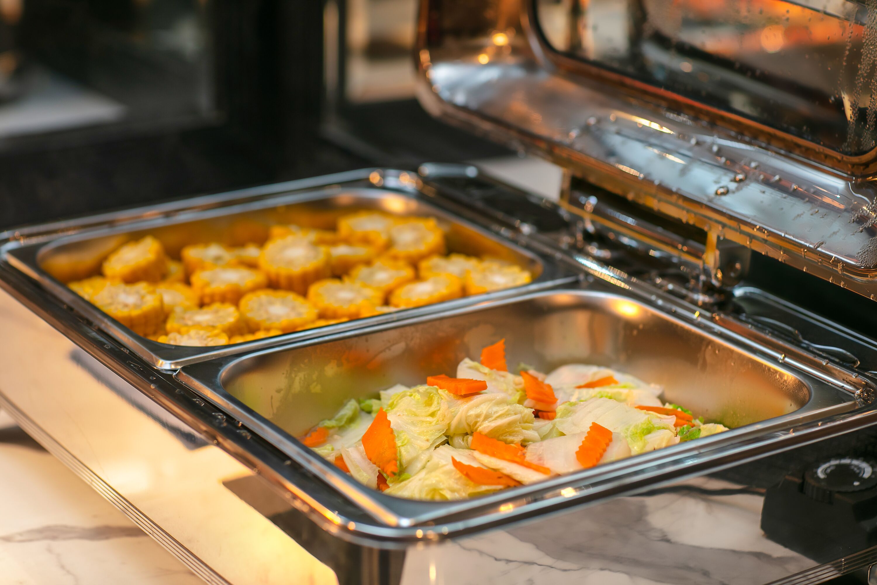 Ein reichhaltiges Buffet mit verschiedenen Speisen, darunter Mais und ein Salat mit Gemüse.
