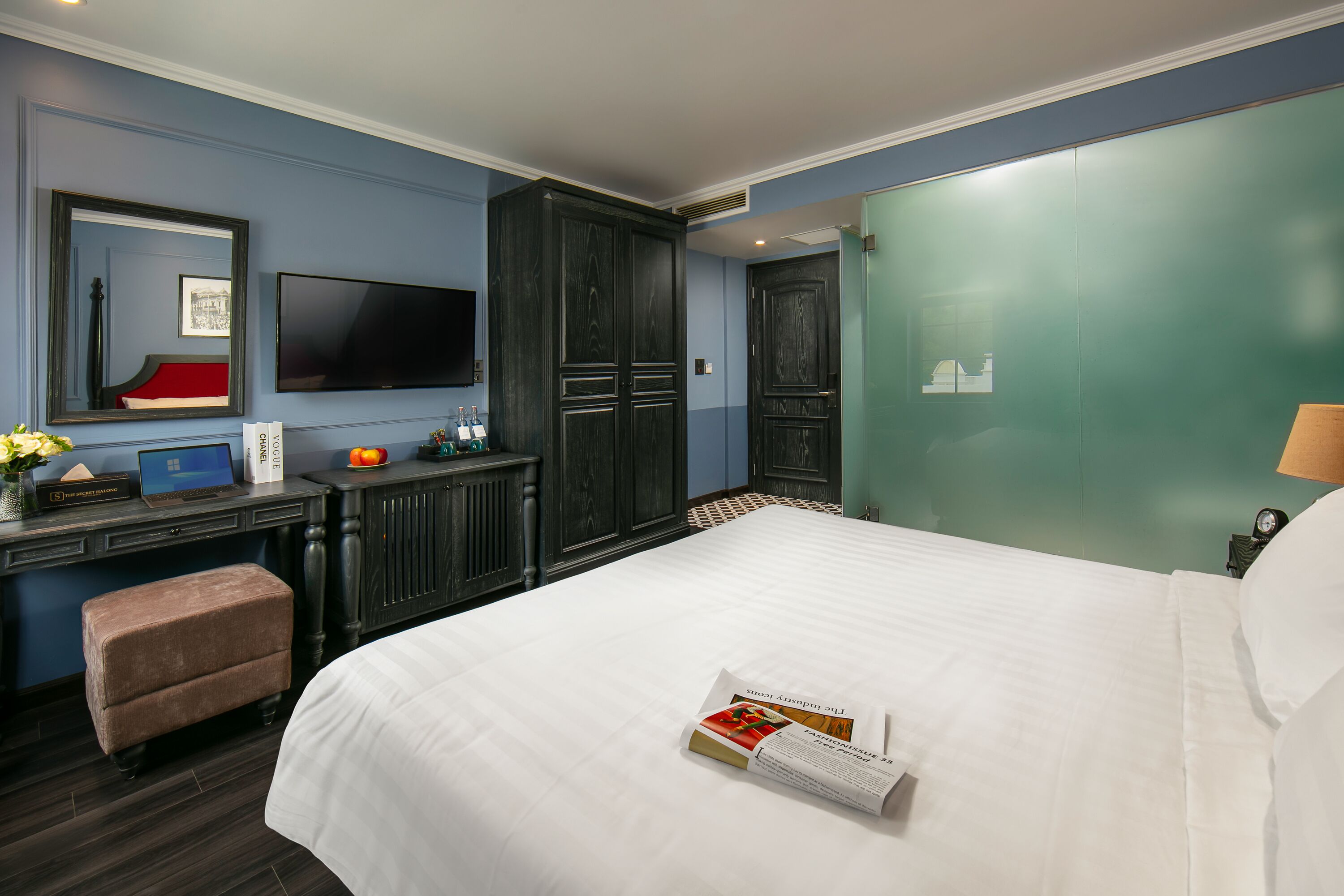 Une chambre d’hôtel avec un grand lit, un bureau avec un ordinateur portable, une télévision et une armoire.