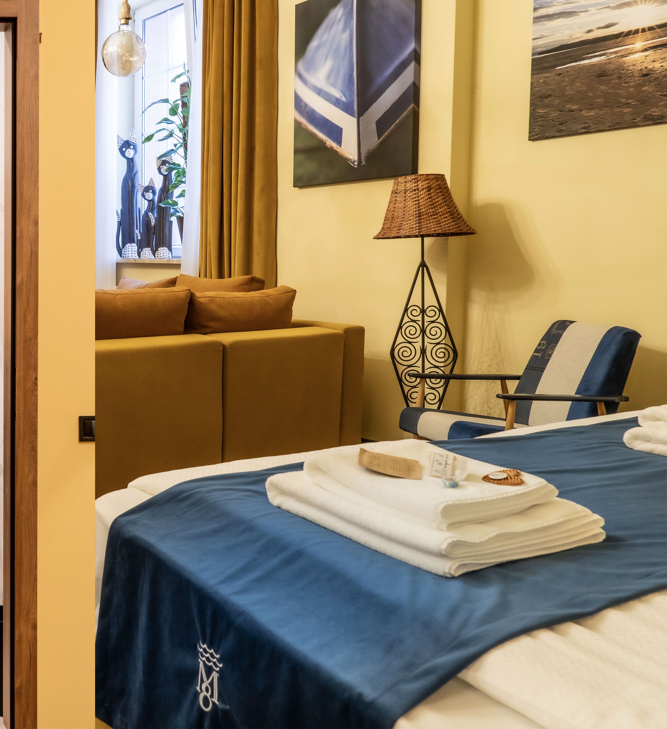 Une chambre d’hôtel avec un lit, une chaise, une lampe et une fenêtre avec des rideaux.