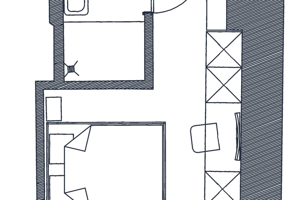 Un plano de planta que muestra una habitación central amplia, una habitación más pequeña con una puerta y un baño.