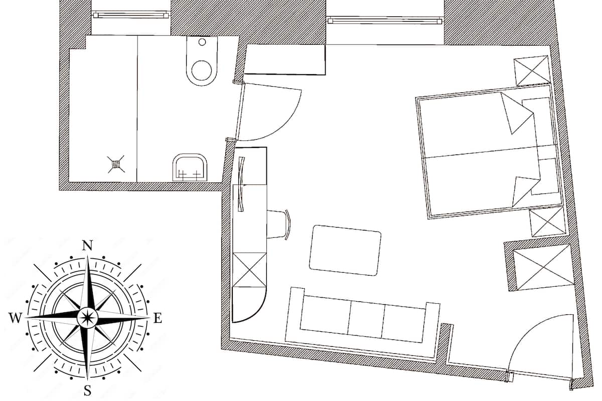 A floor plan of a hotel room with a bed, a desk, a chair, a wardrobe, and a bathroom.