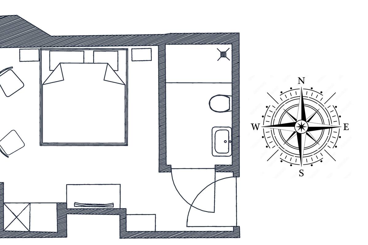 Plano de planta de una habitación de hotel que incluye una cama, un escritorio, una silla, una mesita y una ventana.