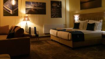 A hotel room with a bed, a chair, a lamp, and wall art.