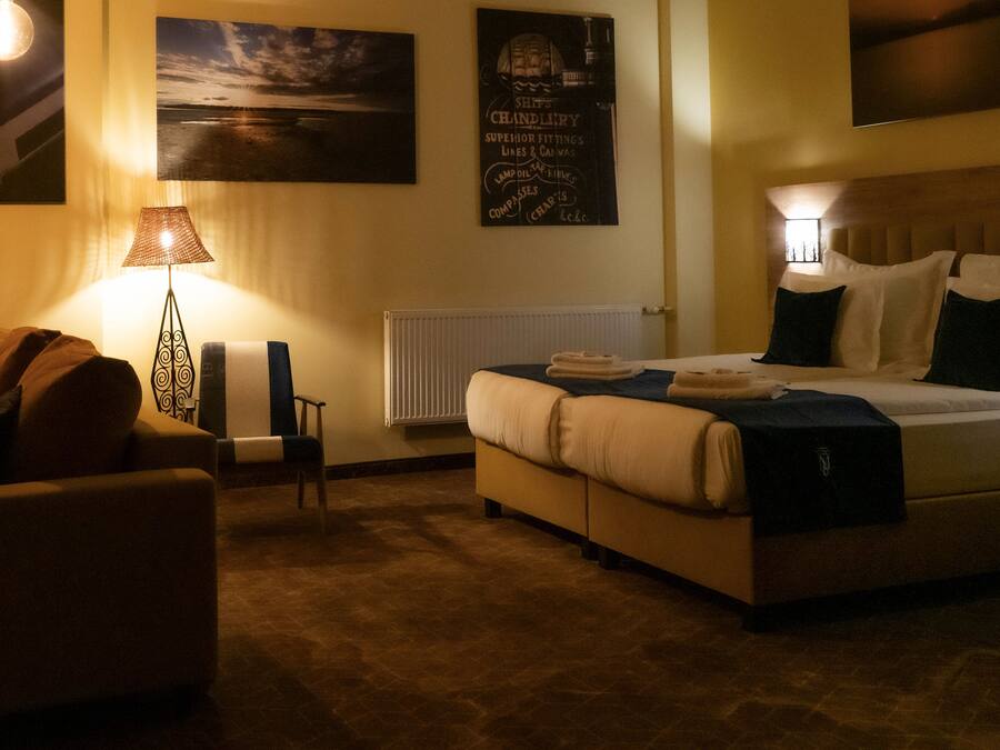 A hotel room with a bed, a chair, a lamp, and wall art.