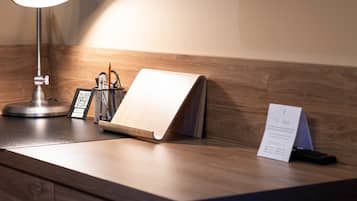 Una scrivania con lampada da tavolo, un blocco note, un portapenne e un telecomando per la TV.