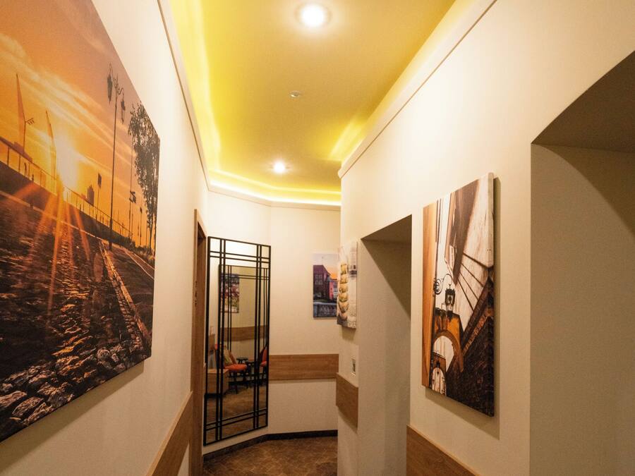 A hallway with a patterned floor, a glass partition, and artwork on the walls.