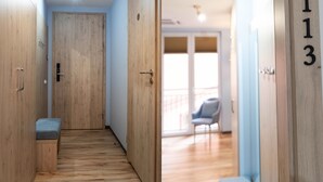 Een hal met houten deuren, een bankje en een stoel in een kamer met een balkon.