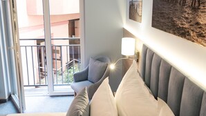 Een hotelkamer met een bed, een stoel, een wandlamp en uitzicht op een buitenbalkon.