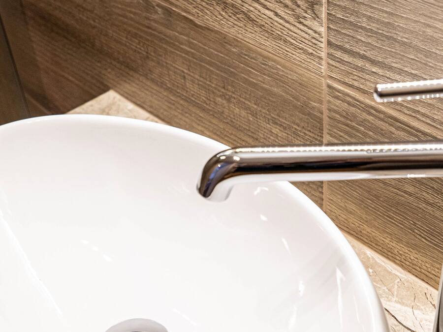 Ein weißes Waschbecken mit Armatur aus Chrom in einem Badezimmer mit Holzvertäfelung.