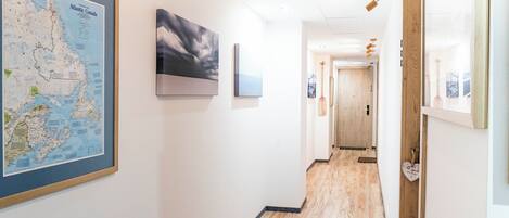 A hallway with a framed map of Atlantic Canada, a painting, and a wooden door at the end.