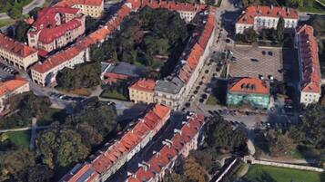 Vista aérea de un pueblo histórico con edificios de tejados rojos, una iglesia destacada y un área de estacionamiento.